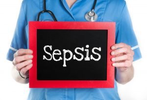 Enfermera sosteniendo letrero con la palabra SEPSIS